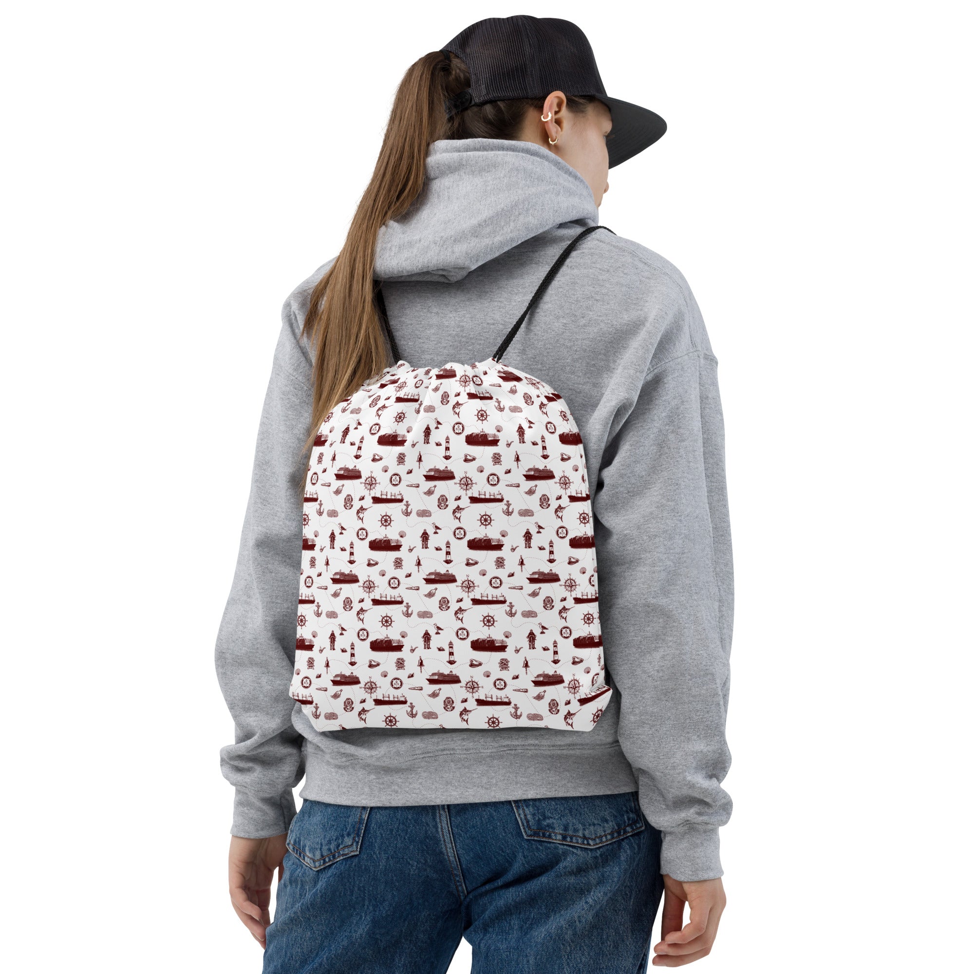 Person wearing a gray hoodie and blue jeans with a patterned backpack on a white background