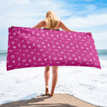 Person holding a pink towel with maritime symbols on a beach