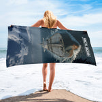 Person holding a beach towel with a ship design on a beach