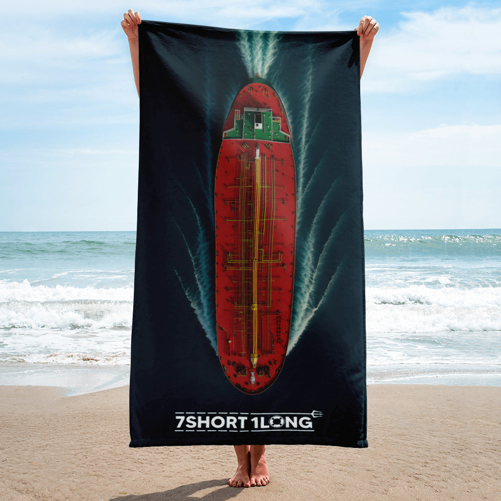 Person holding a beach towel with a red green Tanker Ship on teh beach