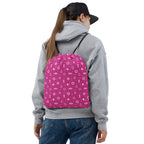 Person wearing a gray hoodie and blue jeans with a pink dayg bag featuring white patterns on a white background