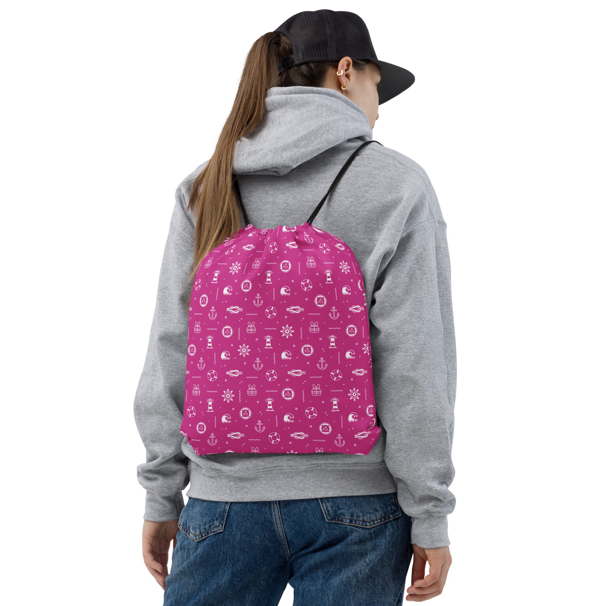 Person wearing a gray hoodie and blue jeans with a pink dayg bag featuring white patterns on a white background