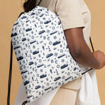 Drawstring bag with nautical pattern worn by a person on a beige background