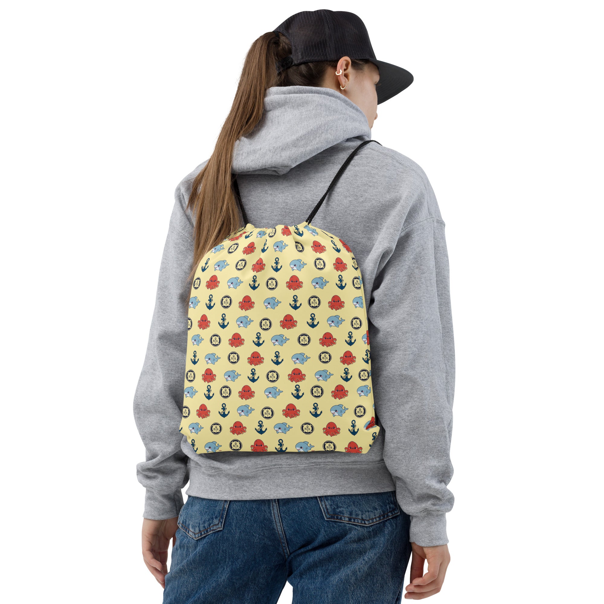 Person wearing a gray hoodie and blue jeans with a colorful patterned backpack on a white background