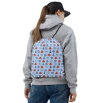 Person wearing a gray hoodie and blue jeans with a patterned backpack on a white background