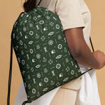 Green drawstring bag with nautical pattern worn by a person on a beige background