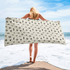 Person holding a large towel with a ocean nautical pattern on a beach