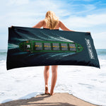 Person holding a beach towel with a boat graphic on a beach