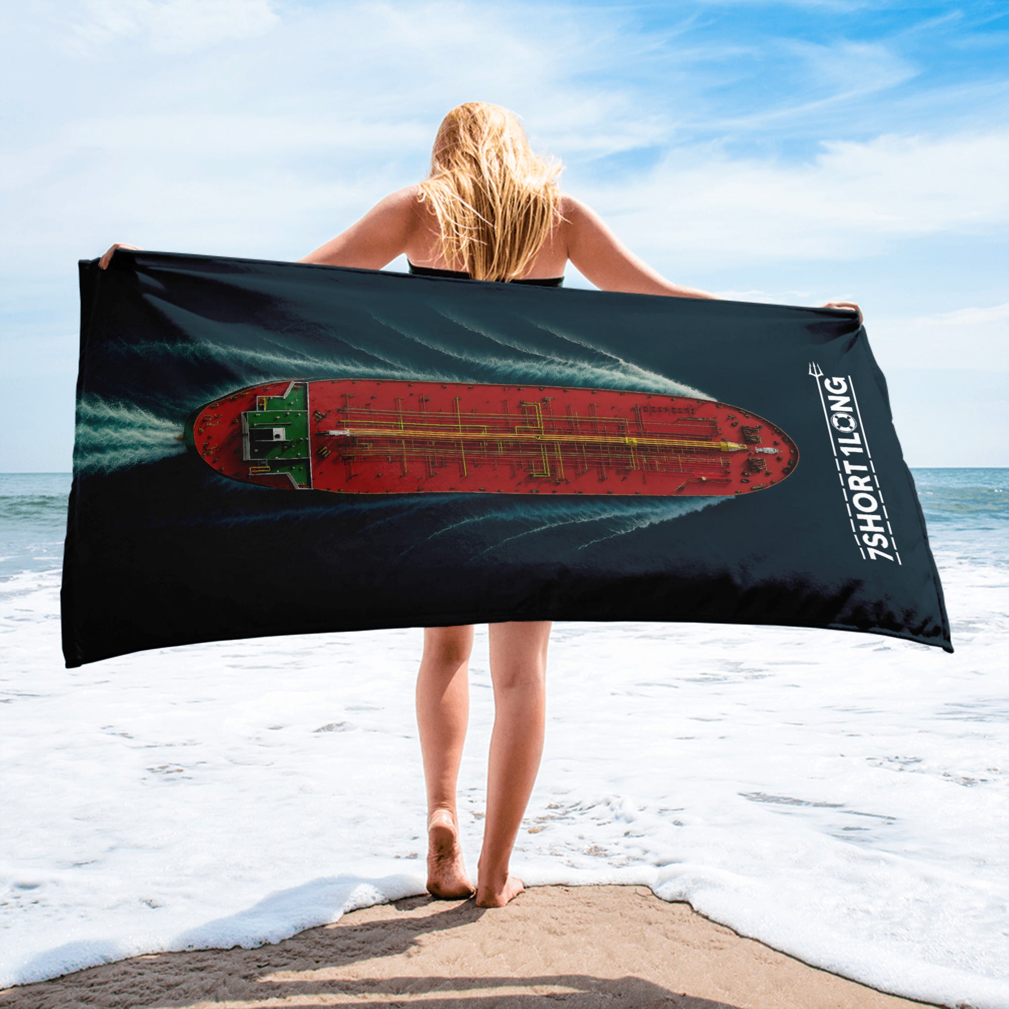 Person holding a beach towel with a ship design on a beach