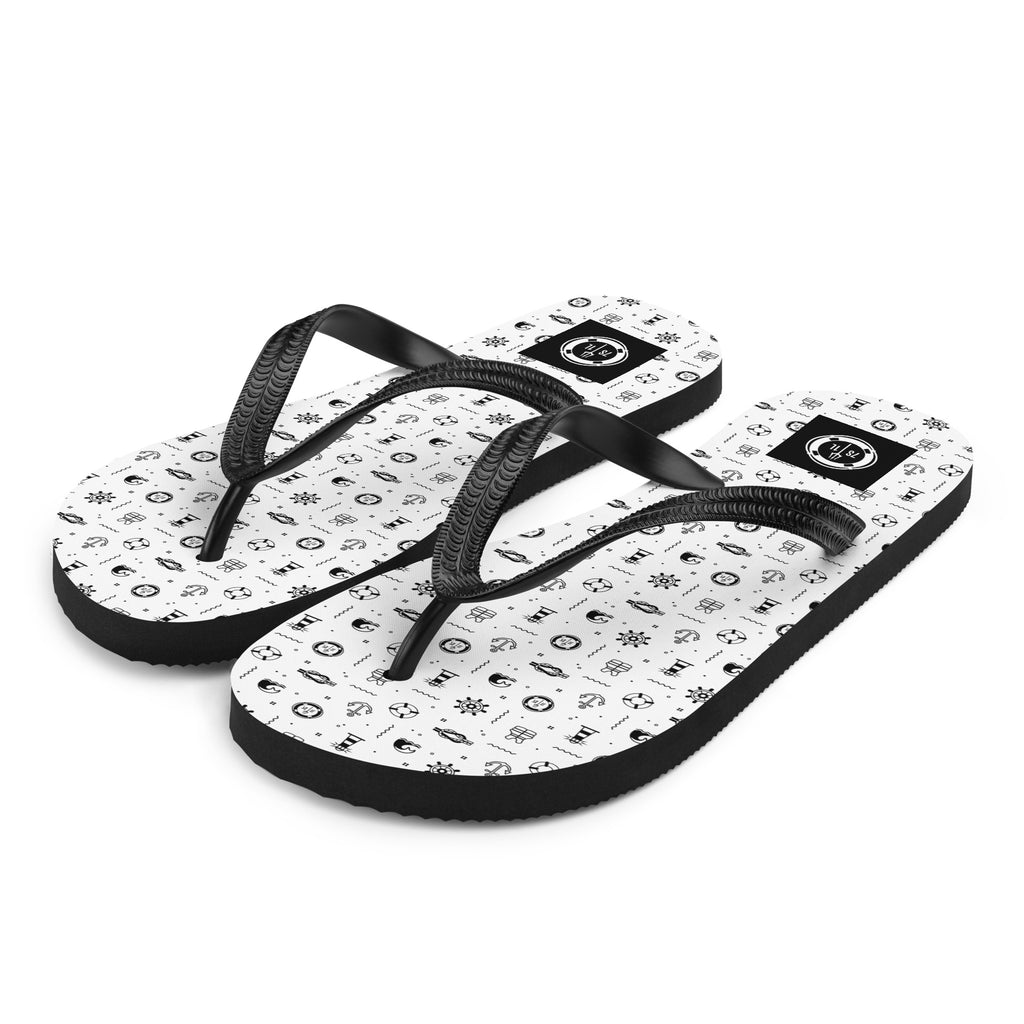 Pair of flip-flops with black maritime pattern on a beach
