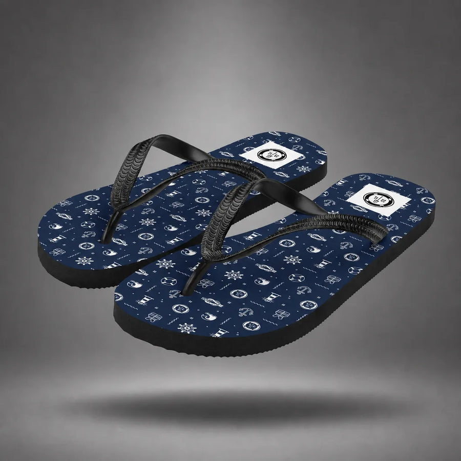 Pair of navy blue Nautical Icon flip-flops with white maritime icon pattern, floating above a grey studio floor with a soft shadow.
