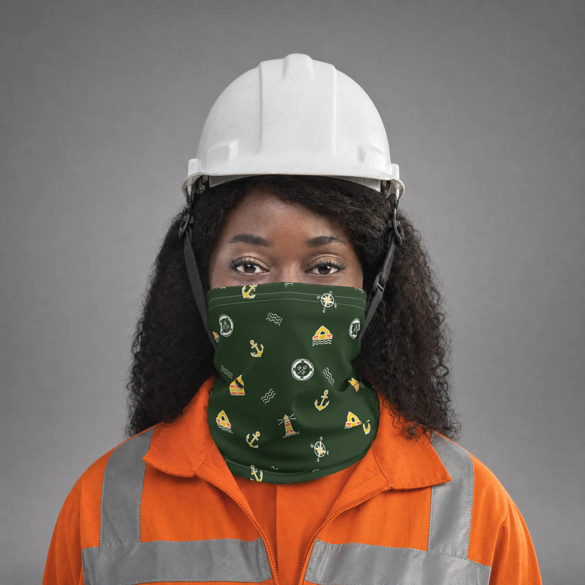 Female seafarer in an orange coverall and white hard hat wearing the green Ocean Adventure neck gaiter over nose and mouth
