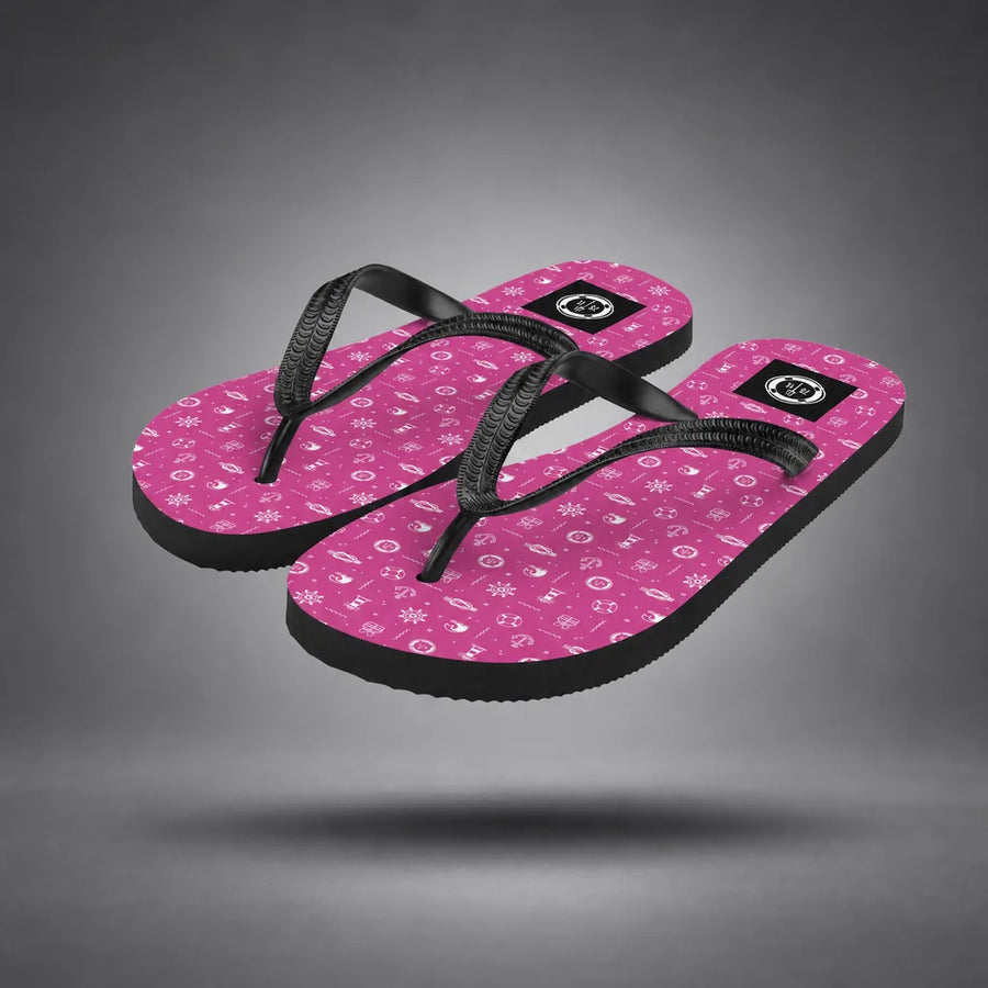 Pair of pink Ocean Explorer flip-flops with white maritime pattern, floating above a grey studio floor with a soft shadow.