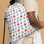 Person holding a drawstring bag with a ocean animal pattern on on a beach 