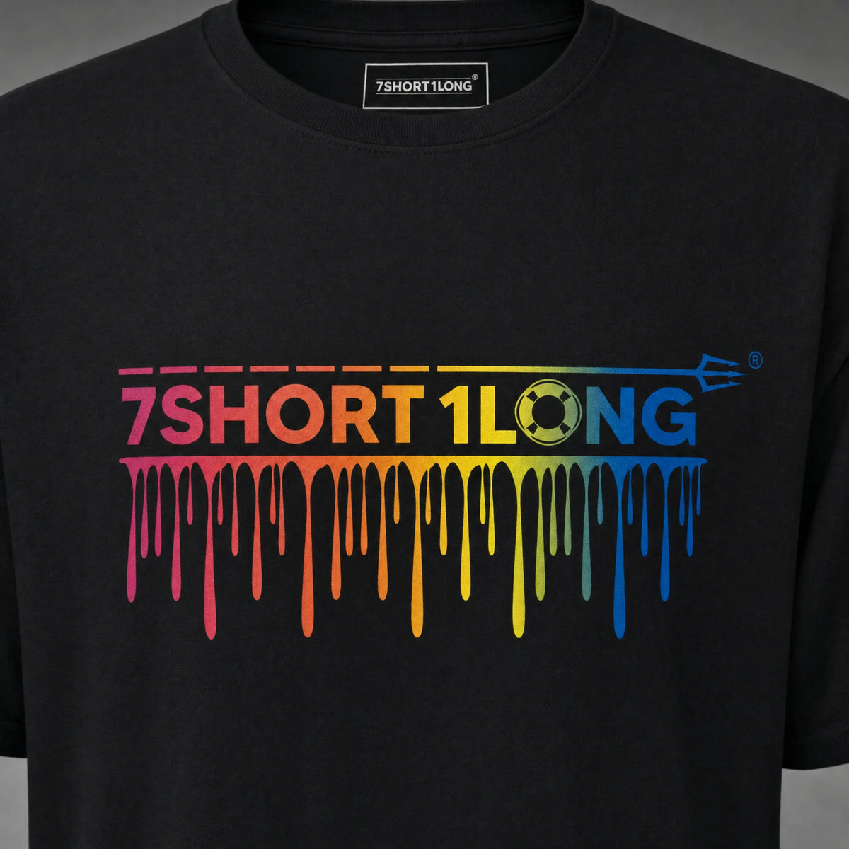 Close view of the rainbow drip wordmark print on the black One Sea One Crew T-shirt, running from magenta through yellow to blue.